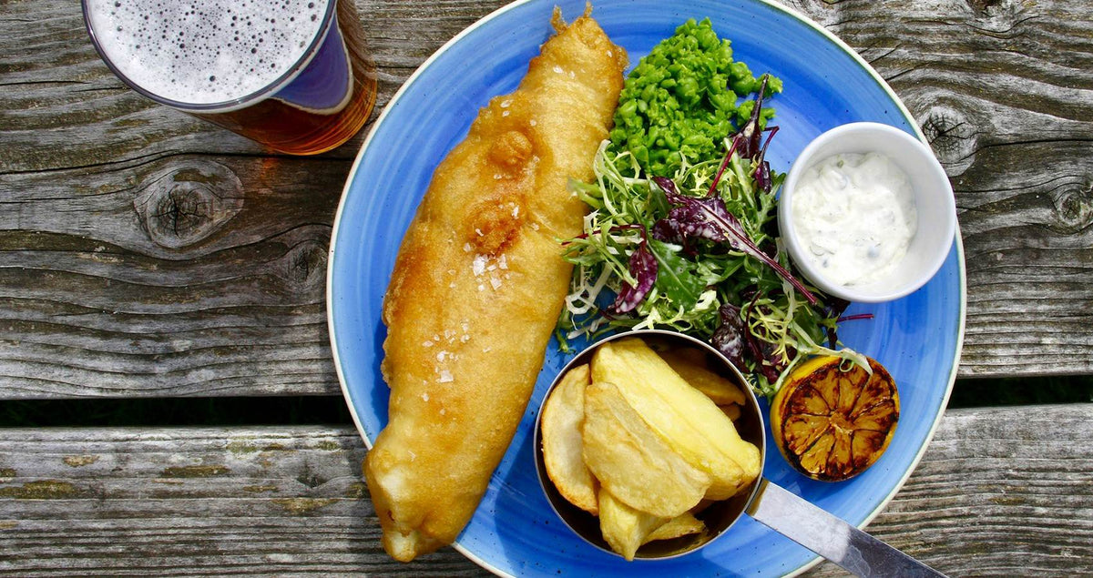 Beer battered fish and chips on a blue plate with salad and tartare sauce