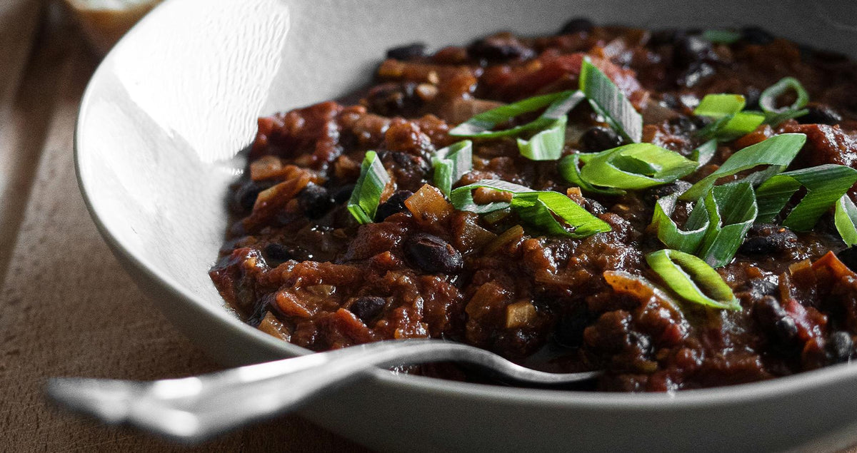 Bowl of beer-infused chilli con carne topped with spring onions