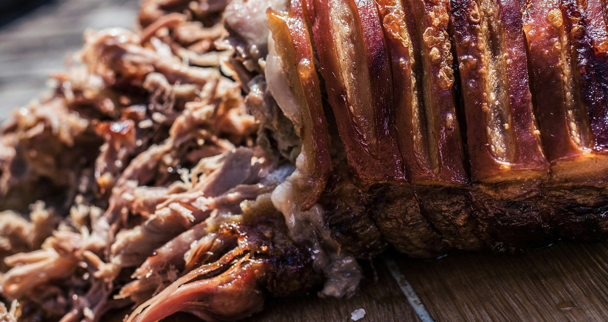 Beer pulled pork piled beside slices of roast pork belly
