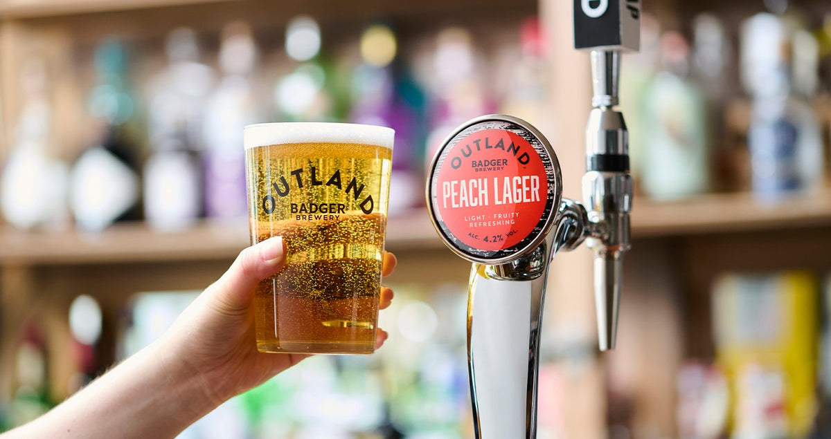 Hand pulling a pint of Outland peach lager from the tap at a bar