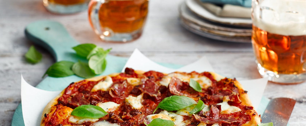 Spicy Fursty Ferret pizza with basil, served with glasses of beer