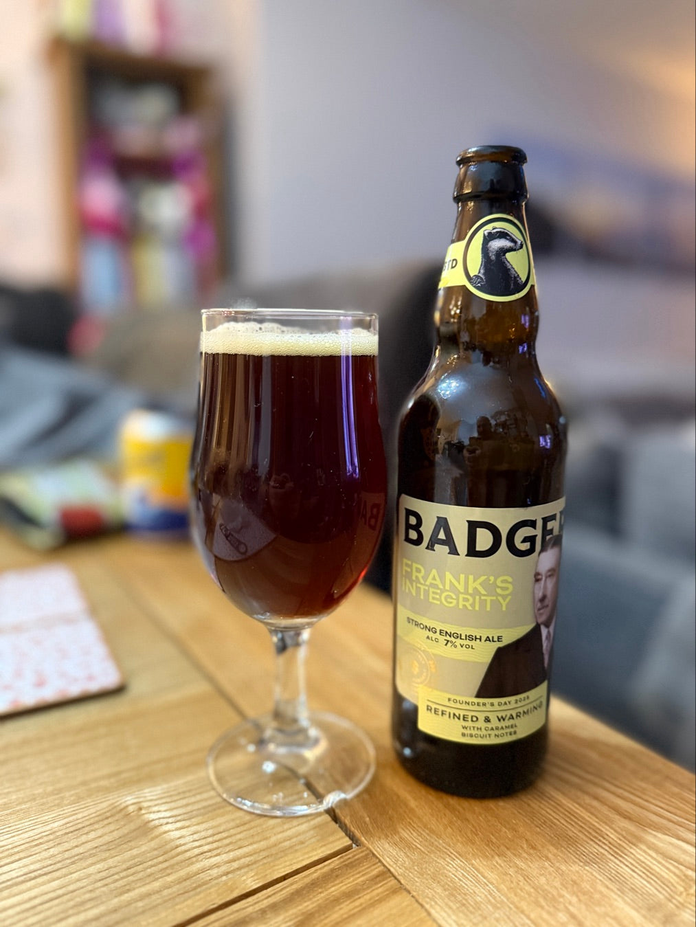 Bottle of Badger ale and a full glass on a wooden table indoors