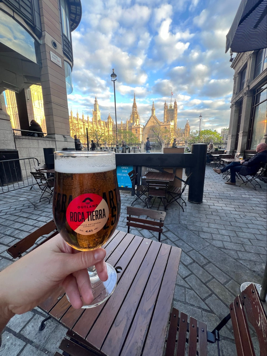 Hand holding a Badger pint glass on a table outside a cathedral