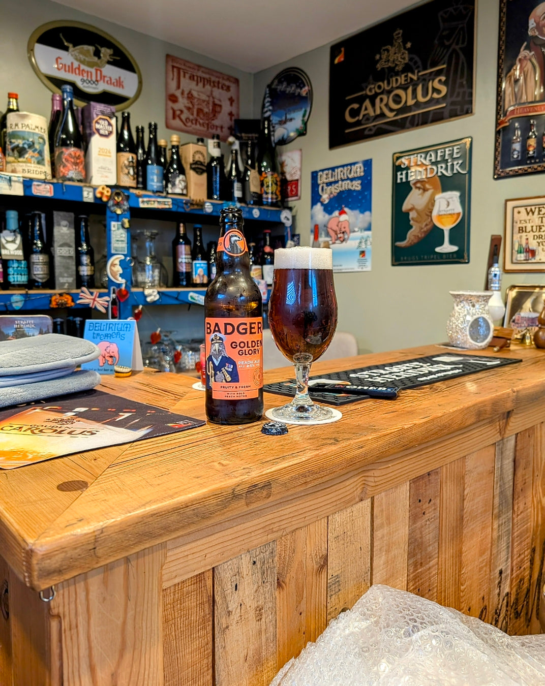 Bottle of Badger ale and a glass on a home bar surrounded by breweriana