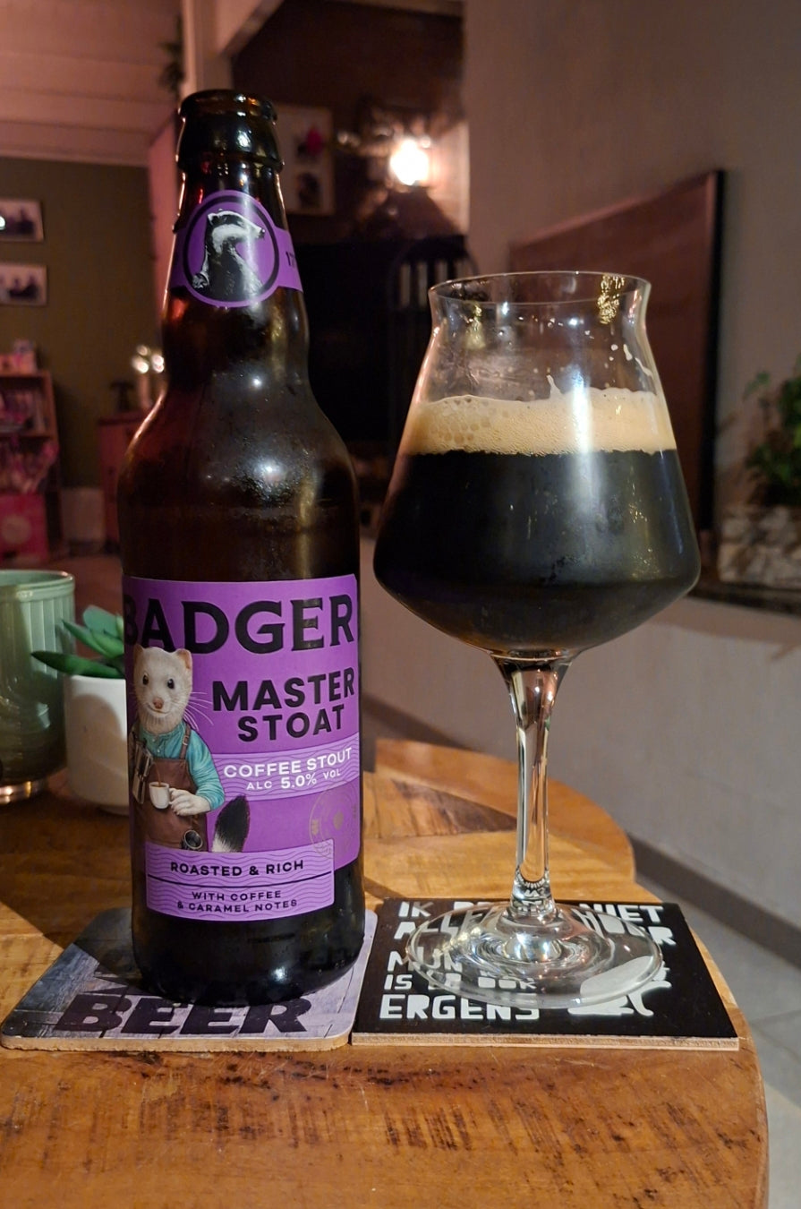 Bottle of Badger Master Stoat and a dark pint in a stemmed glass on a table