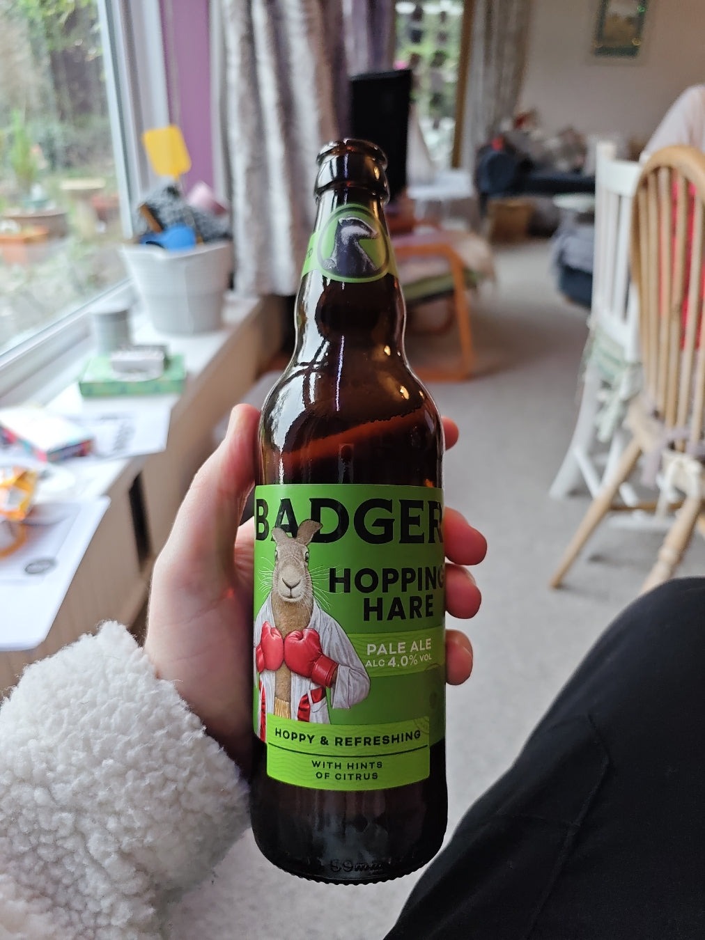 Person holding a bottle of Badger Hopping Hare in a conservatory