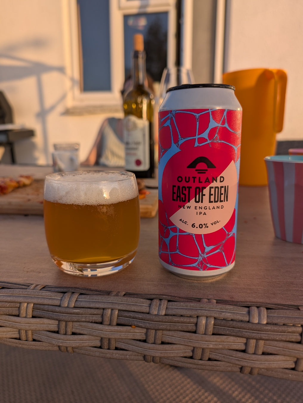 Can of Outland East of Eden and a full glass on a rattan garden table