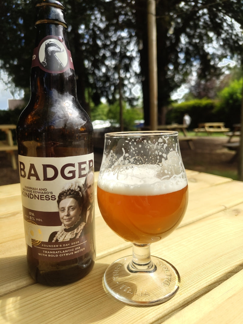 Bottle of Badger Founder's Day ale and a stemmed glass on a garden table