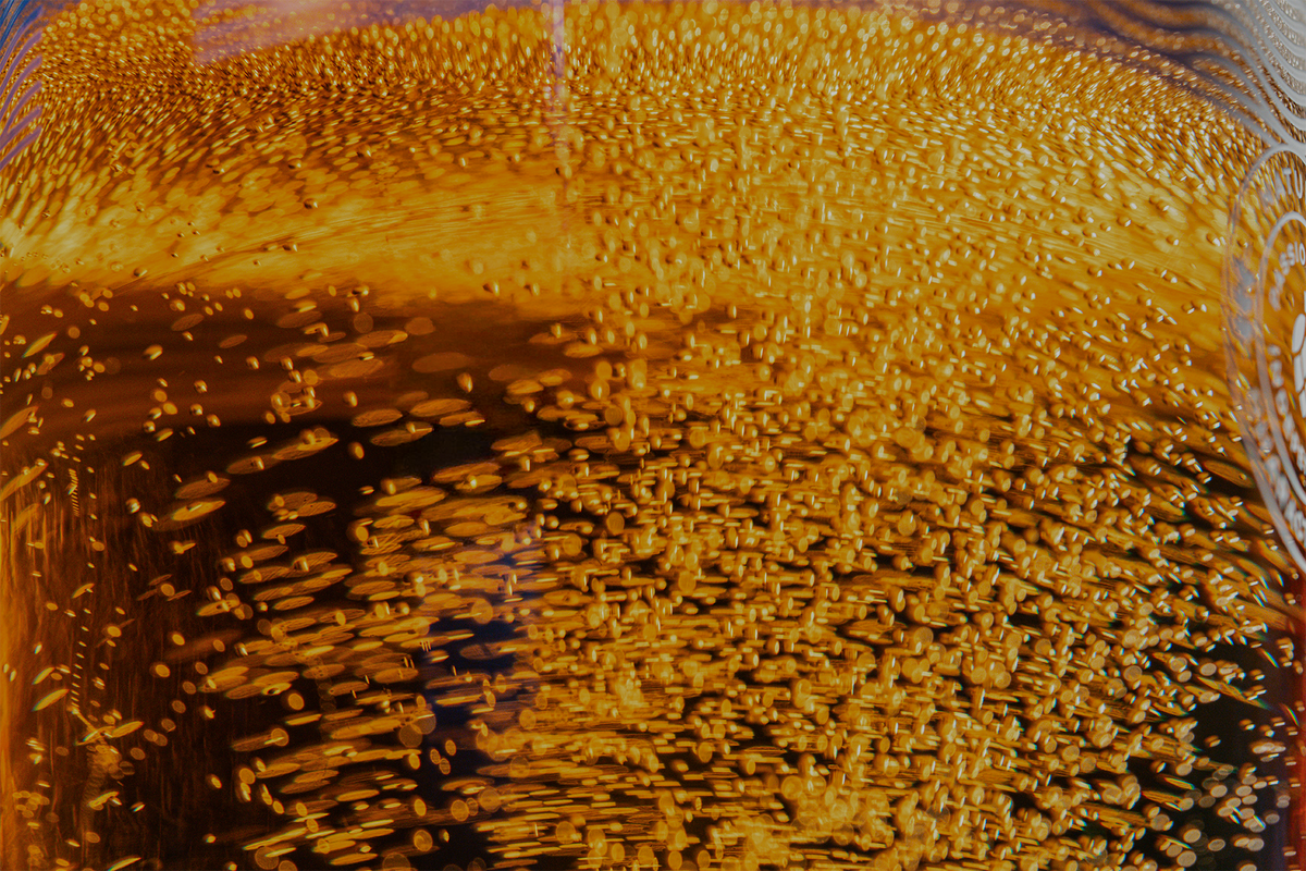 Close-up of a Badger Pale Ale liquid filled with dense fine bubbles, showing a warm yellow-orange tone and bubbly texture.