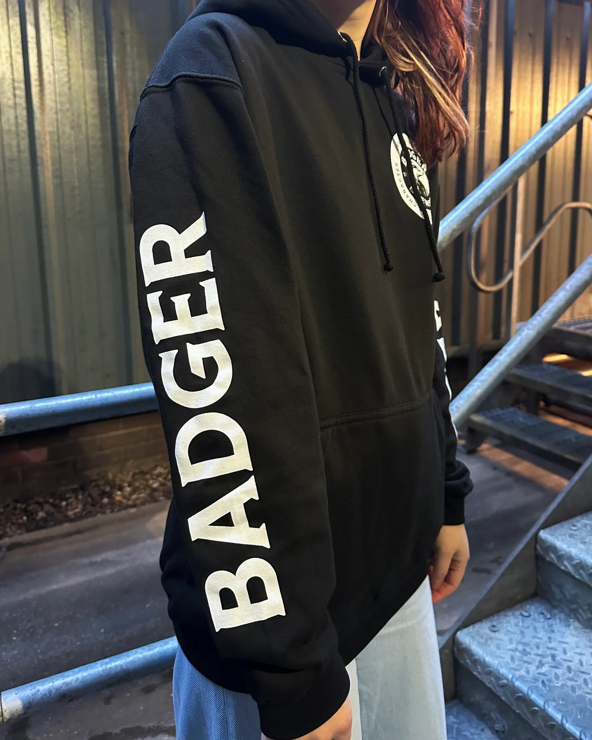 Side view of the black Badger hoodie worn at the brewery with Badger printed down the sleeve