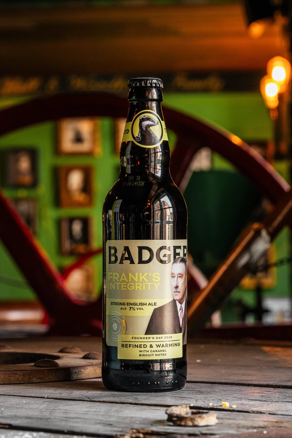 Bottle of Badger Frank's Integrity held in front of the brewery maltings building