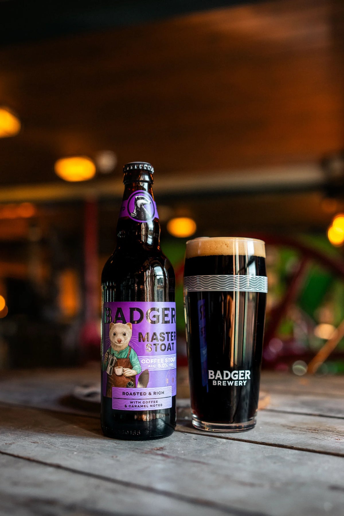 Bottle of Badger Master Stoat and a dark pint on a table in the brewery maltings