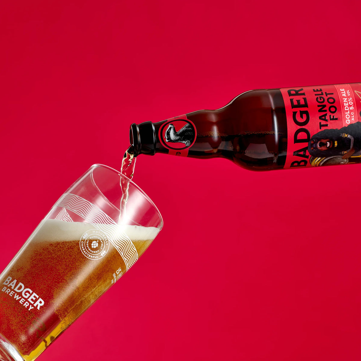 Badger Tangle Foot poured into a branded glass on a red background