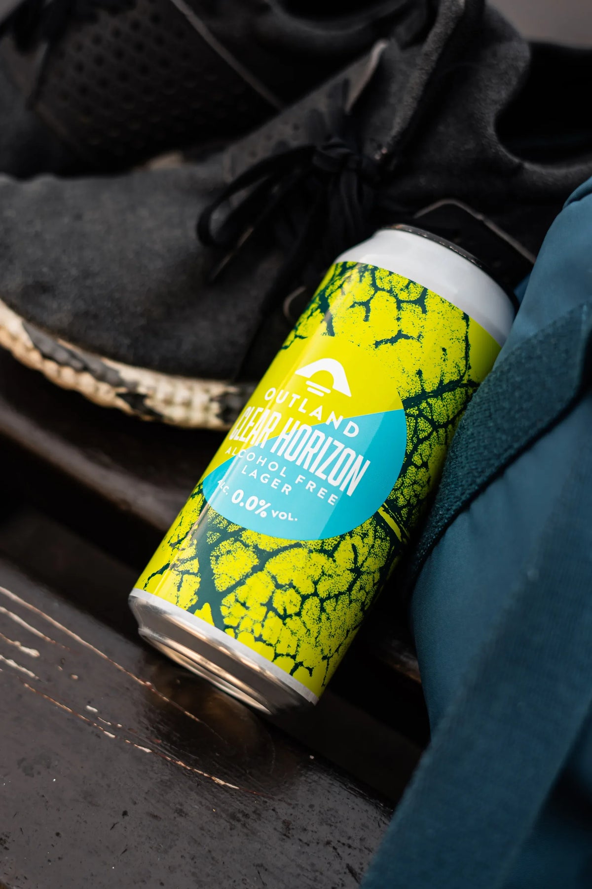 Can of Outland Clear Horizon alcohol-free lager held at the side of a runner in dark kit