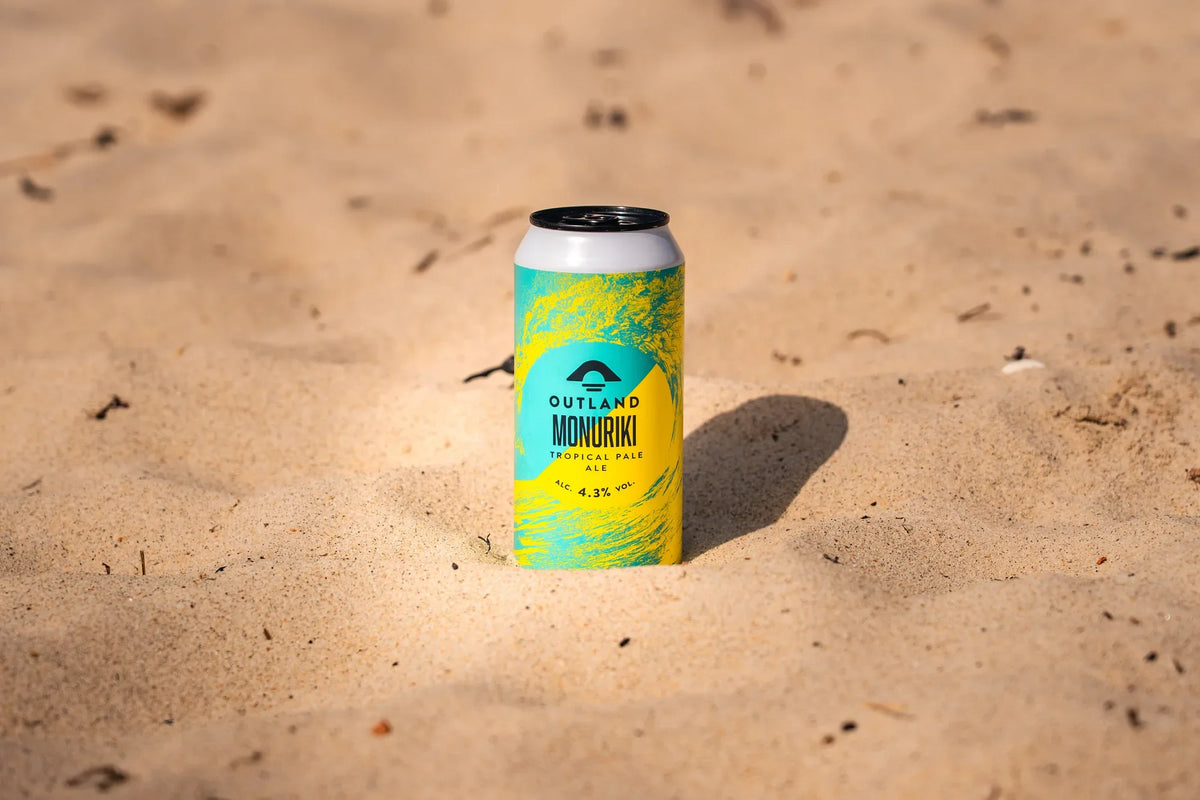 Can of Outland Monuriki standing on rippled sand in low sunlight