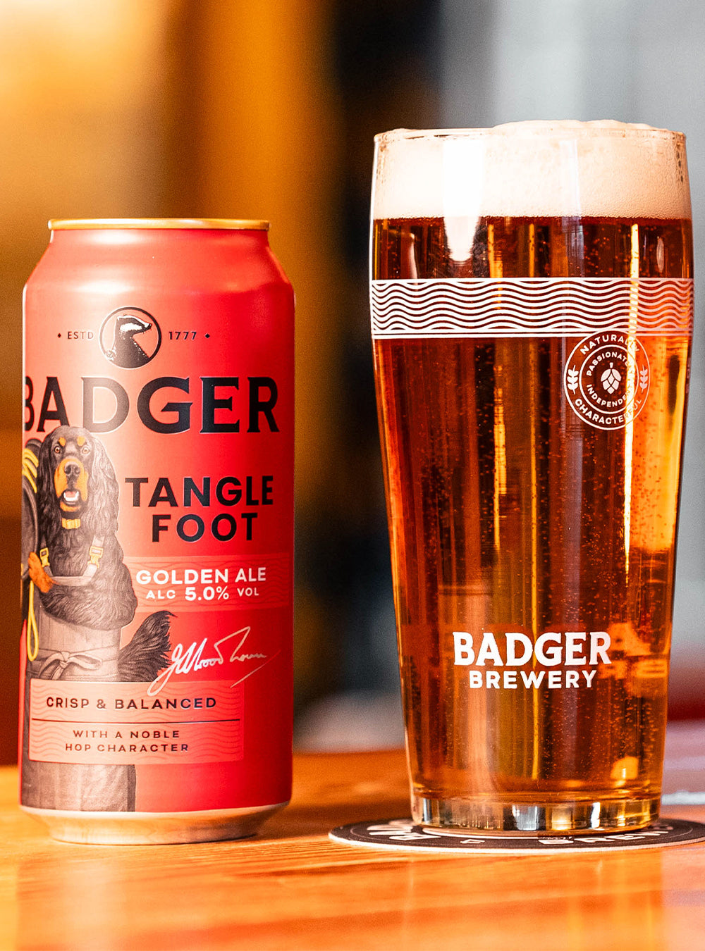 Can of Badger Tangle Foot beside a full branded pint glass