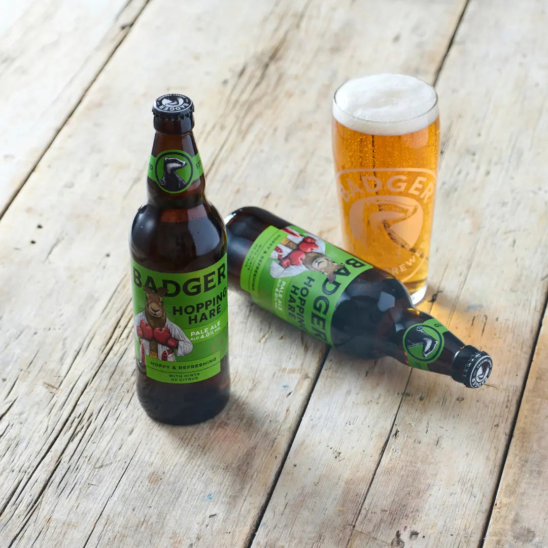 Two bottles of Badger Hopping Hare and a full pint glass on weathered white decking