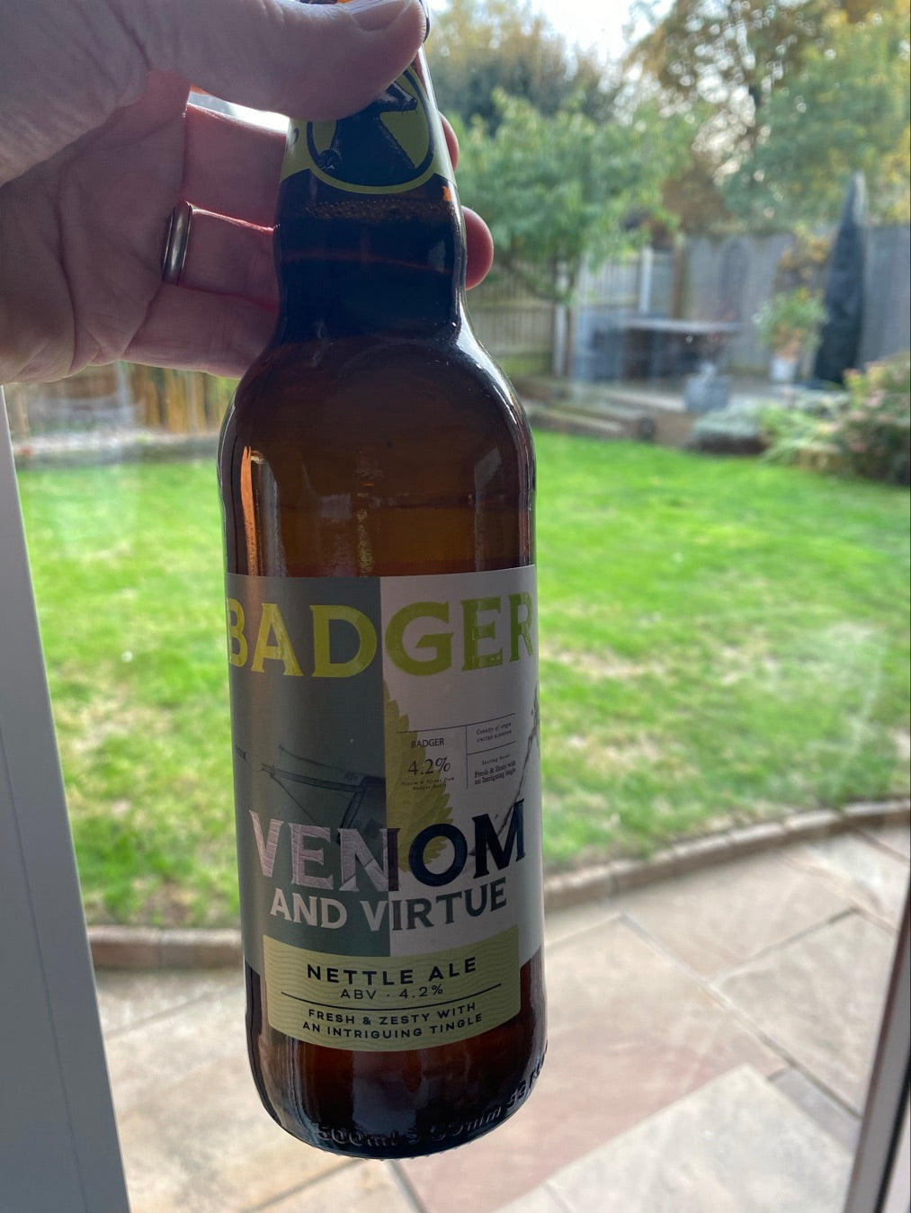 Bottle of Badger Venom and Virtue nettle ale held up in a garden