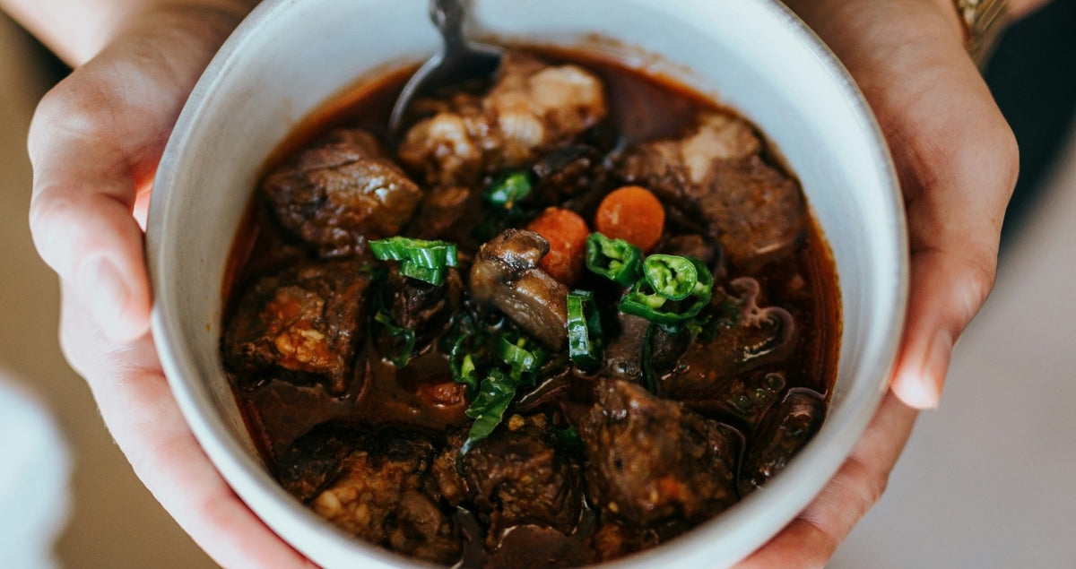 Bowl of beef and beer stew held in two hands