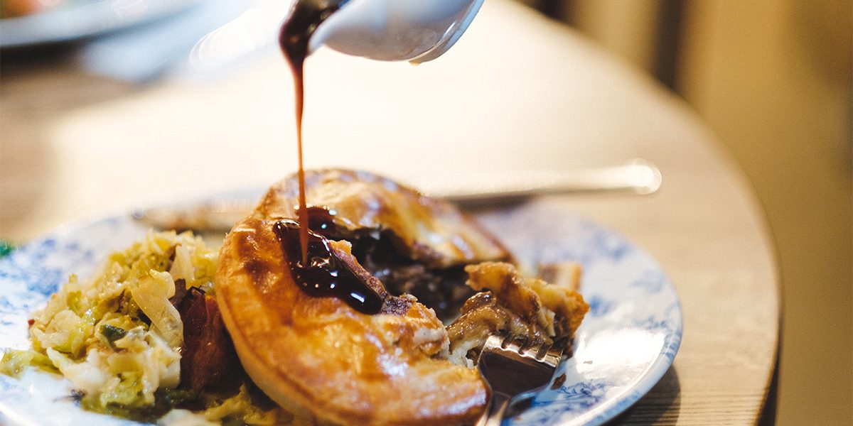 Fursty Ferret steak pie on a plate with gravy being poured over it