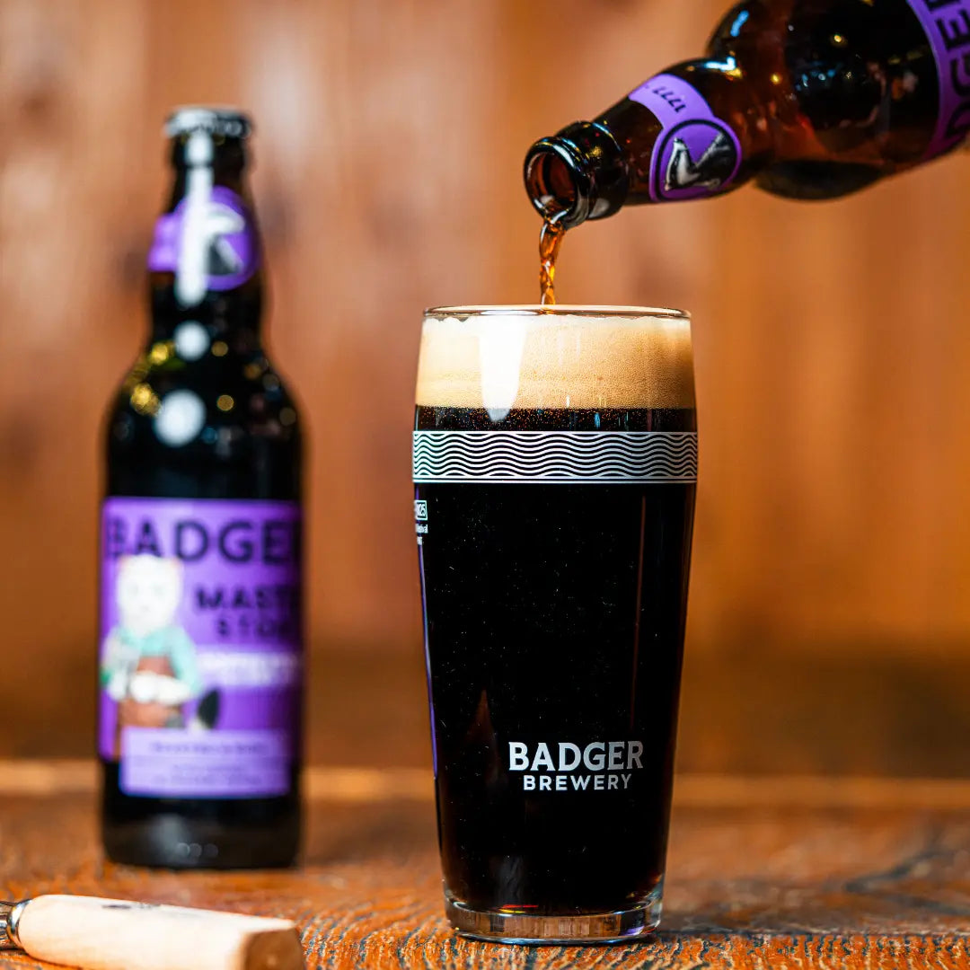 Badger Master Stoat poured from the bottle into a branded pint glass, forming a thick head
