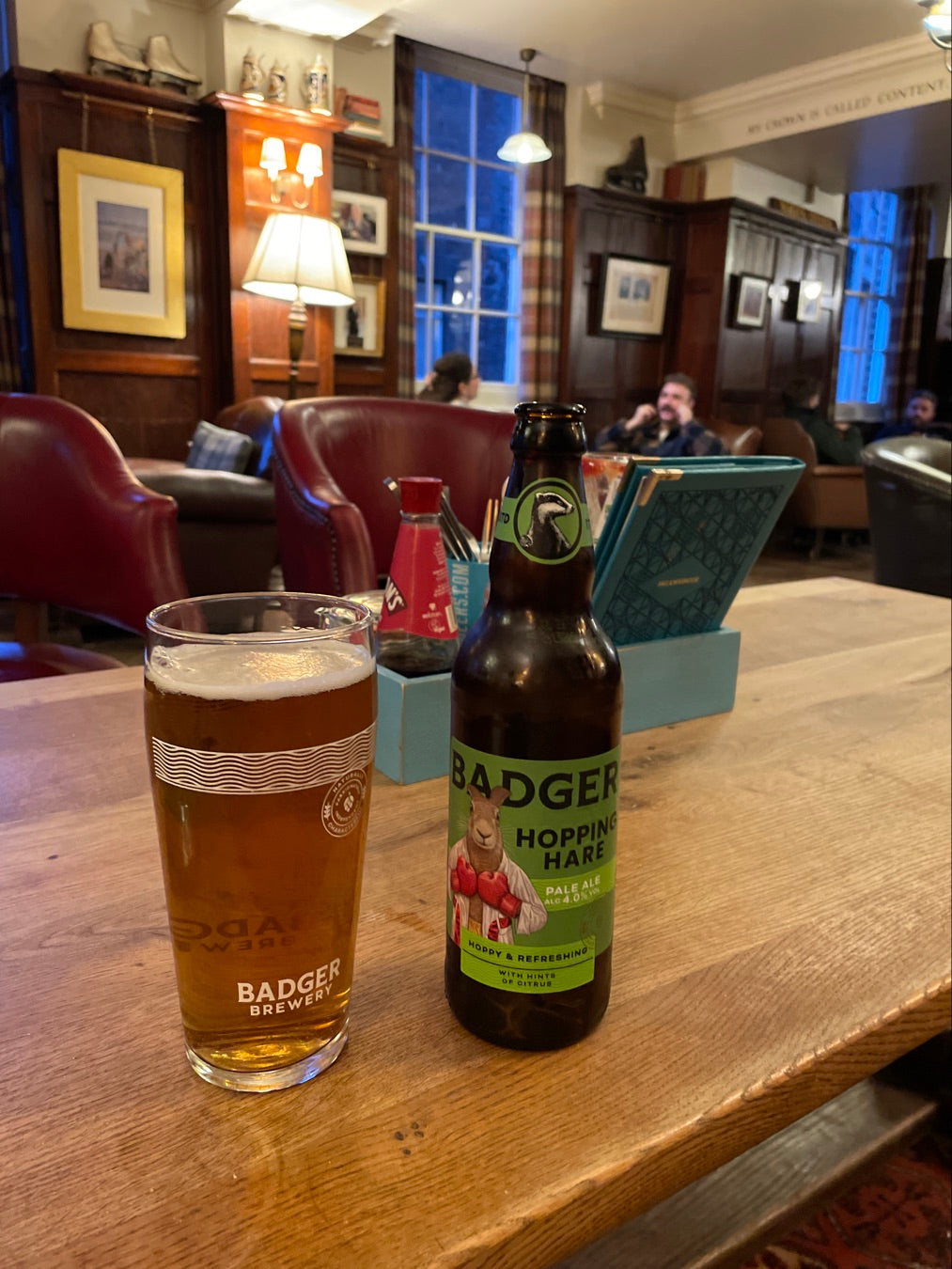 Pint and bottle of Badger ale on a pub table in a wood-panelled bar