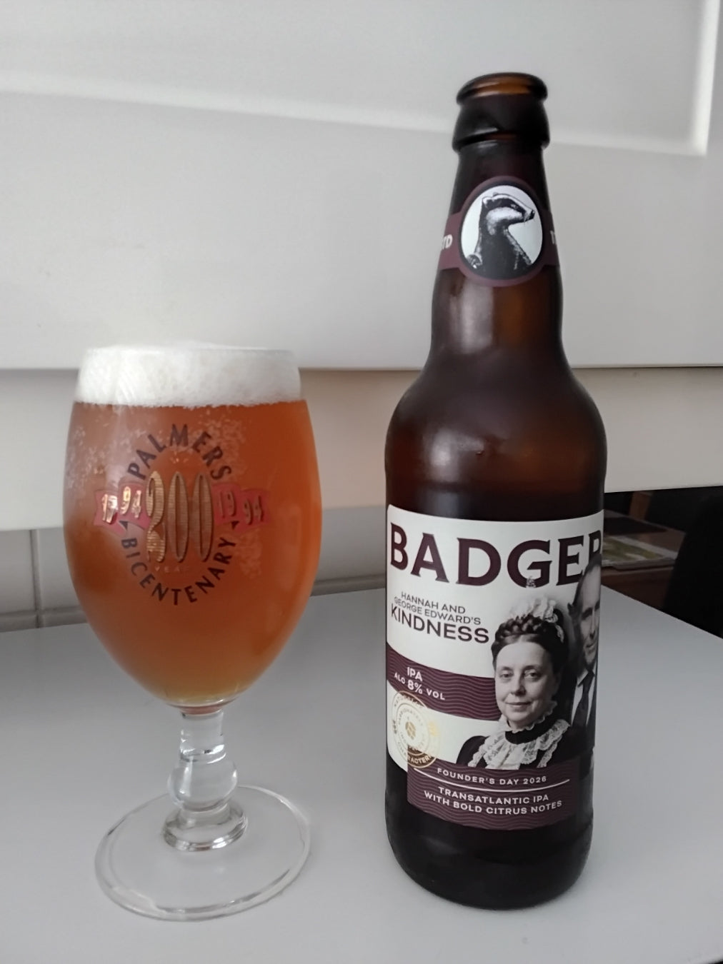 Bottle of Badger Founder's Day ale beside a full stemmed glass indoors