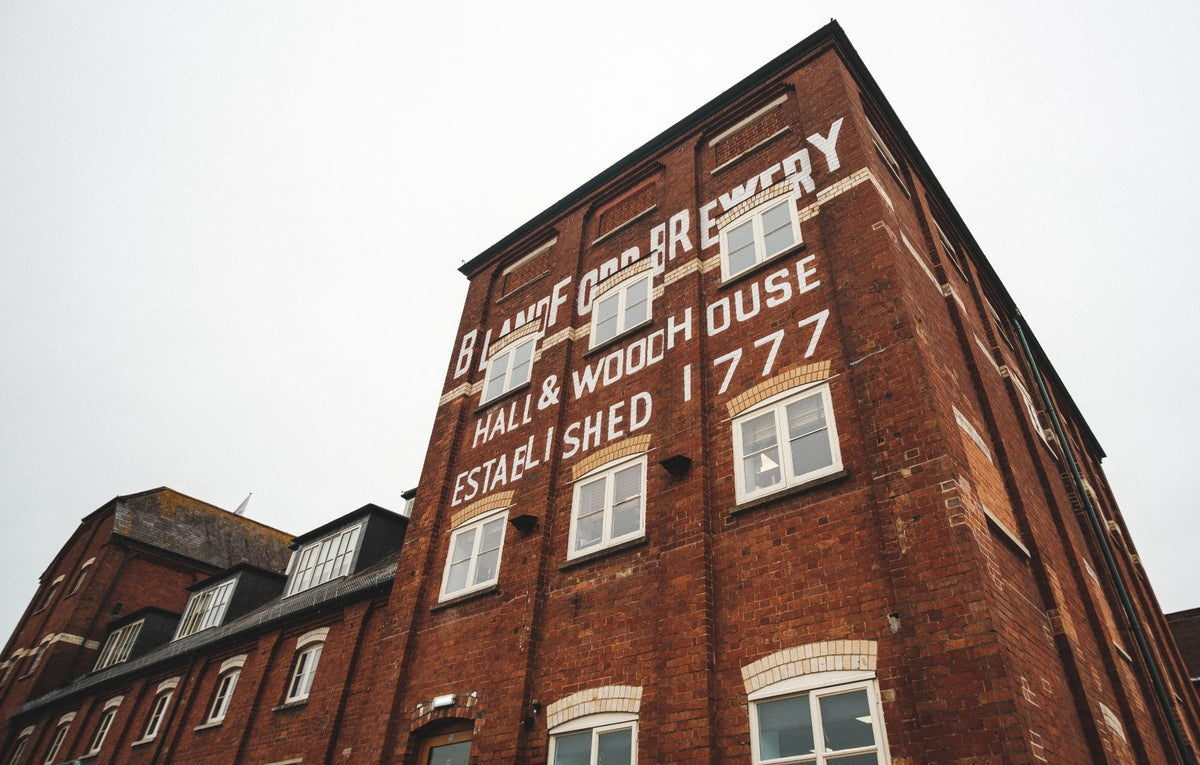 View from below, looking up at the Badger Brewery maltings red brick building, showcasing printed text: Badger Brewery. Hall & Woodhouse established 1777.