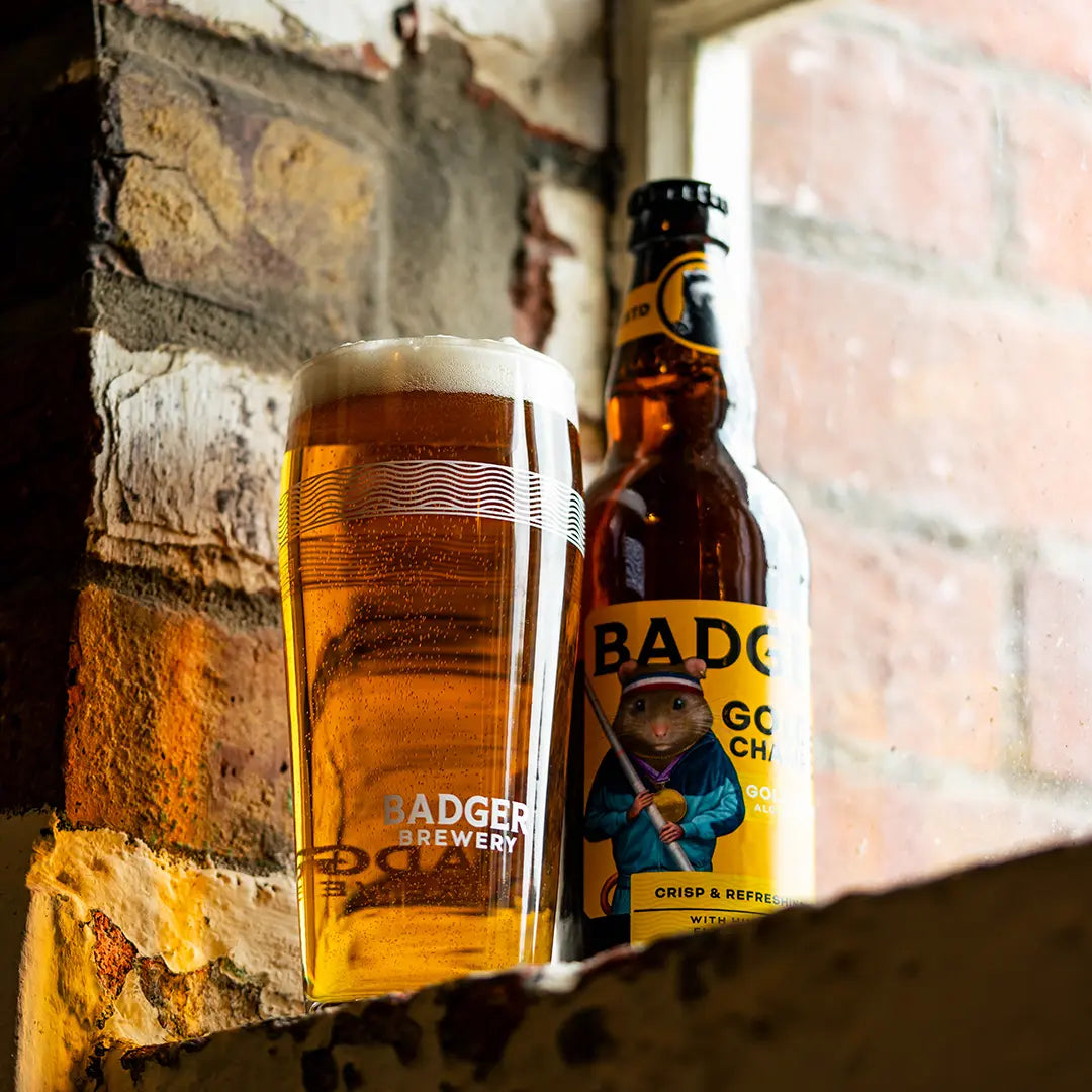 Bottle and full pint of Badger Golden Champion on a stone ledge by a brick wall