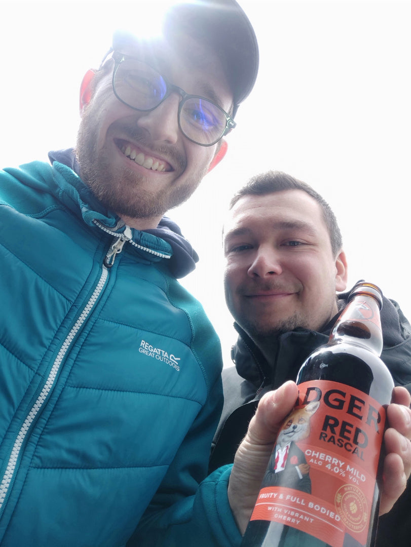 Two people smiling while holding bottle of Badger Red Rascal beer