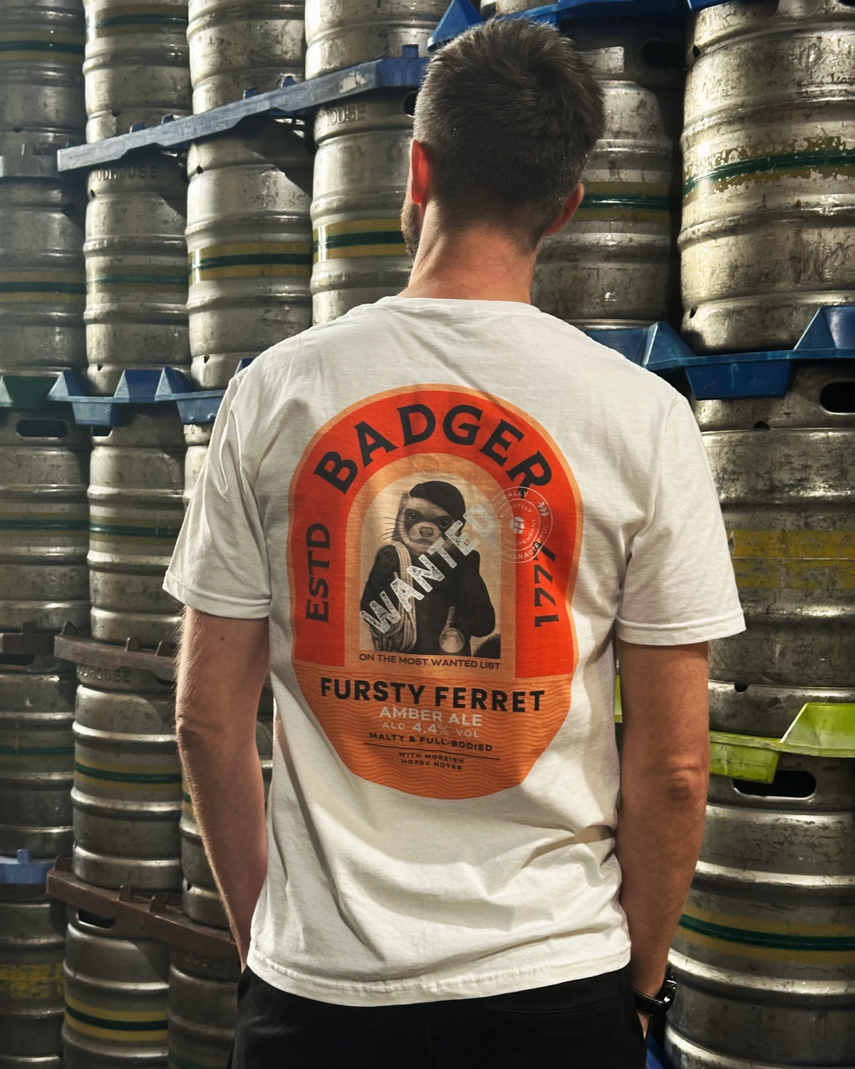 Man wearing the white Fursty Ferret t-shirt in the brewery cask store, showing the back print