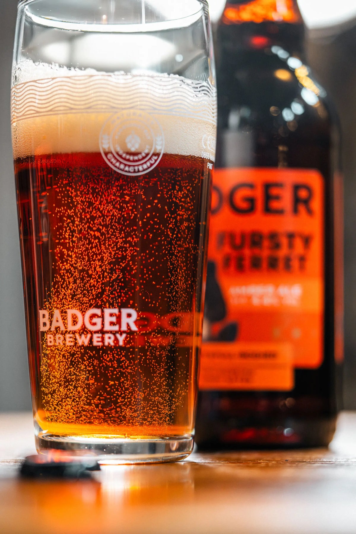 Close-up of a Badger Fursty Ferret bottle beside a full pint of amber ale
