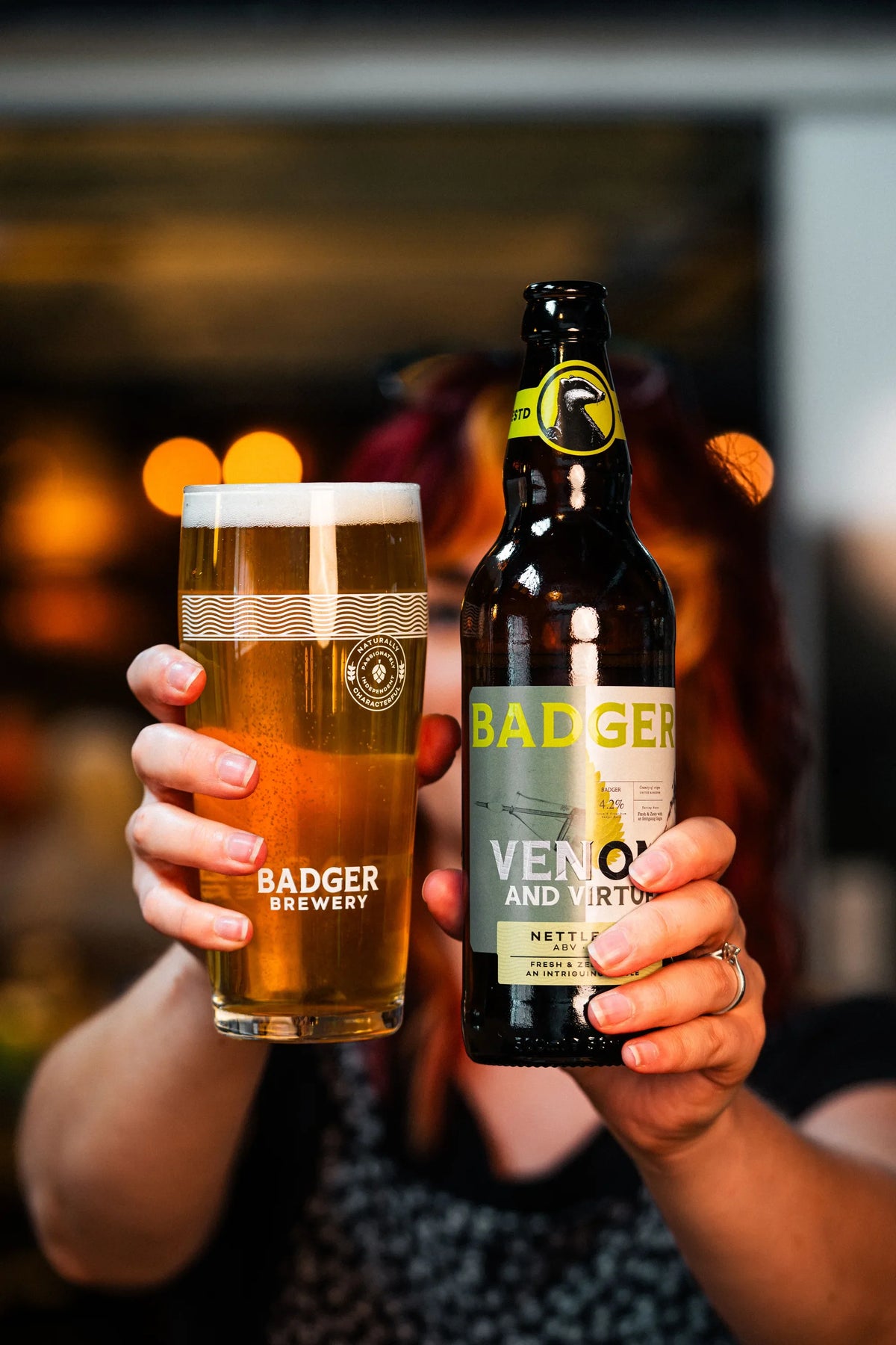Two people holding a pint and a bottle of Badger Venom and Virtue nettle ale