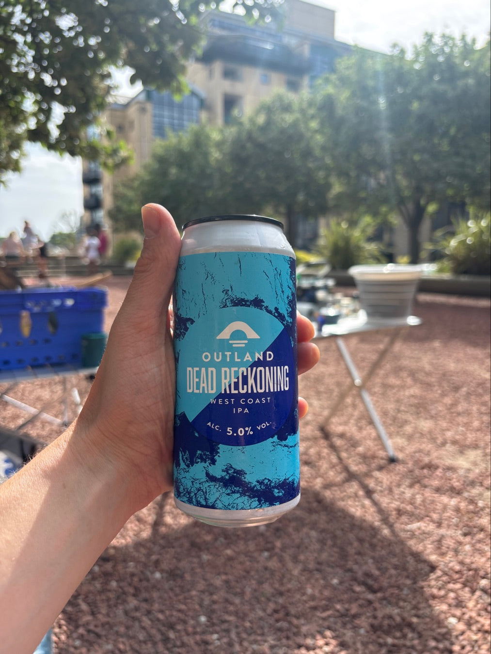 Can of Outland Dead Reckoning held up in a resort courtyard