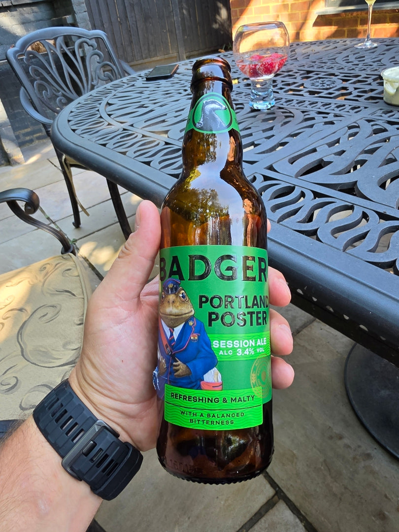 Hand holding a bottle of Badger Portland Poster over a metal garden table