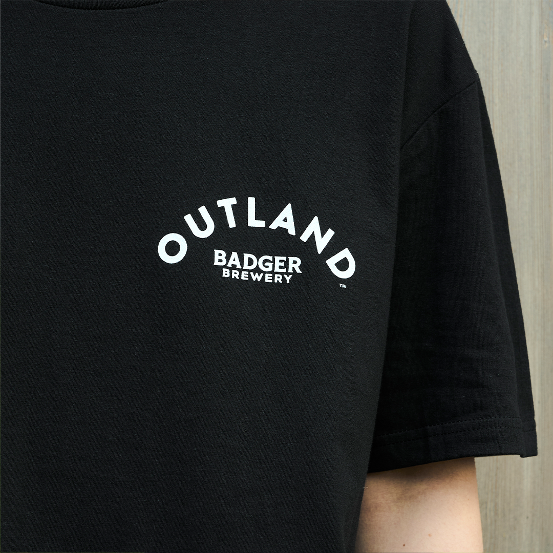 Person wearing Outland Black T-shirt (Up Close of Logo)