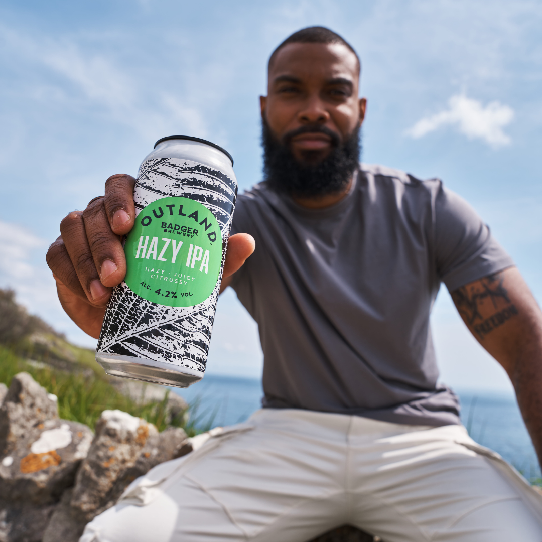 Person holding Outland Hazy IPA outdoors