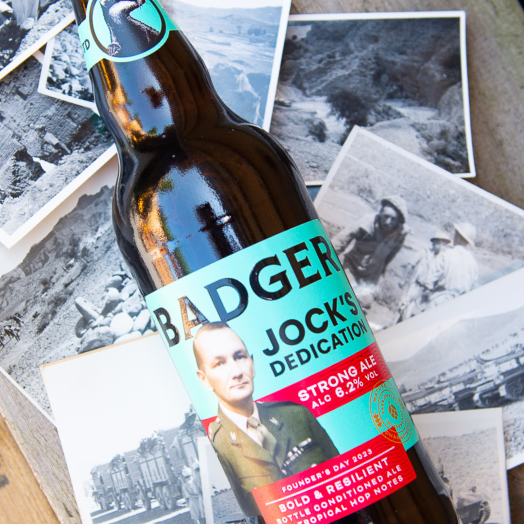 Bottle of Jock's Dedication Strong Ale lying on old photos
