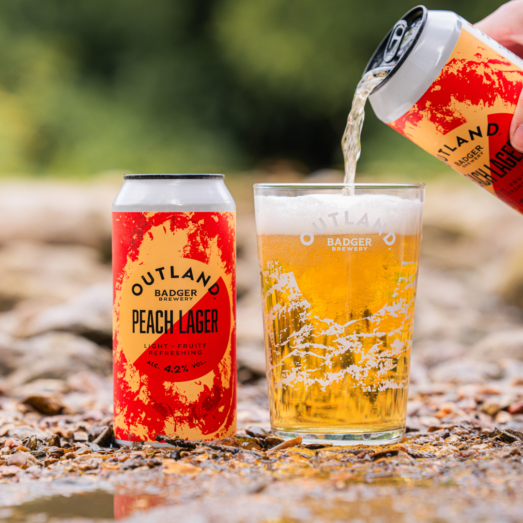 Can of Outland Peach Lager pouring into glass