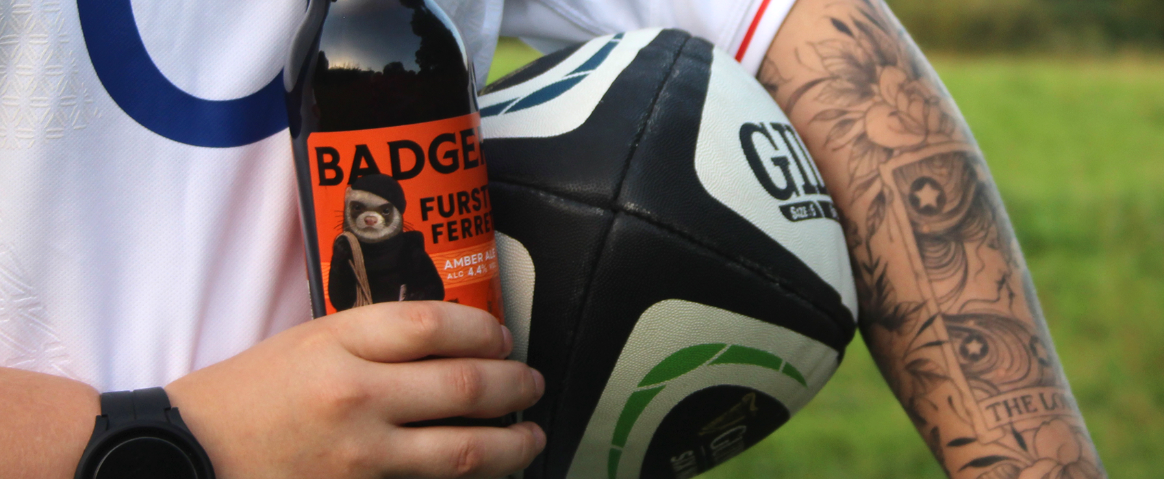 Person holding bottle of Fursty Ferret and Rugby Ball