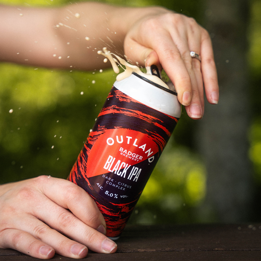 Person opening can of Outland Black IPA
