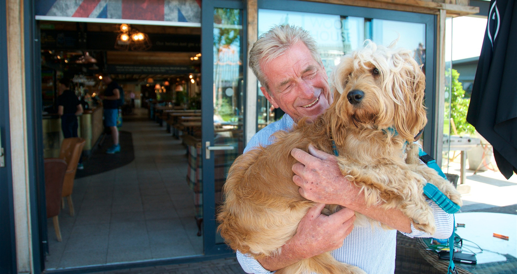 Person holding dog outside of a Hall and Woodhouse dog friendly pub