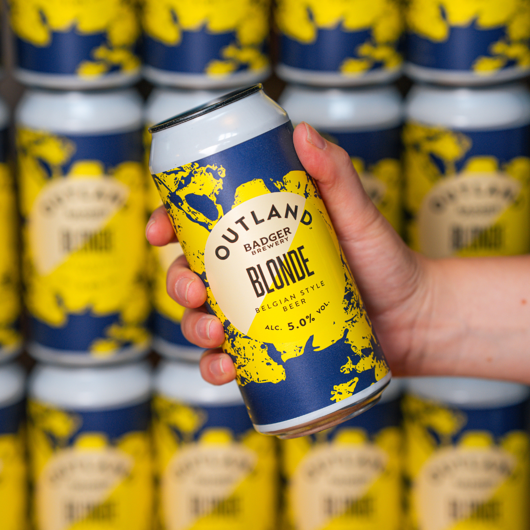 Person holding can of Outland Blonde Belgian Beer